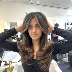 A beautiful color refresh with face-framing highlights. The lighter pieces around the face brighten the entire look, and the hair is styled in voluminous curls.