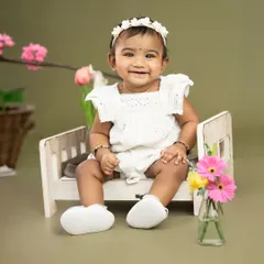 A happy smile from a sweet baby girl sitting on a miniature bed prop. Sitter sessions are perfect for capturing these joyful milestones.