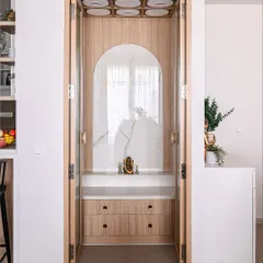 This elegant puja unit is designed with a light wood frame and a marble-patterned backdrop. The folding doors allow it to be neatly closed off when not in use.
