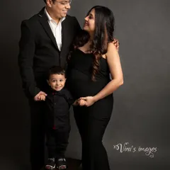 From three to four. This classic family portrait in matching black outfits is a sophisticated and timeless way to capture the family's excitement for their new arrival.