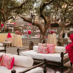 This lounge area for a Mehfil-e-Mehendi features traditional Indian daybeds with plush white cushions and vibrant pink pillows. The setting is both regal and relaxed, perfect for an evening of music and celebration.