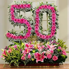 A magnificent floral arrangement celebrating a 50th birthday. We created the number "50" using bright pink roses and baby's breath, set above a large trough of lilies and other beautiful flowers.