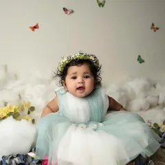 A sweet, curious expression from this six-month-old baby girl. The whimsical butterfly and cloud backdrop adds a touch of magic to her milestone portrait.