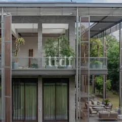 We designed this modern home to breathe with its natural surroundings. The structure uses raw concrete, warm wood, and expansive glass to dissolve the boundaries between the interior and the lush greenery outside, creating a seamless indoor-outdoor living experience.