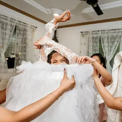 A playful and chaotic moment as the bridesmaids help the bride into her voluminous wedding dress. It's these fun, real moments that make the day.