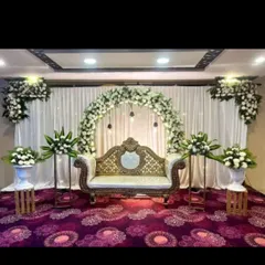 A simple and classic engagement decor with a white floral arch, hanging bulbs, and a traditional sofa.