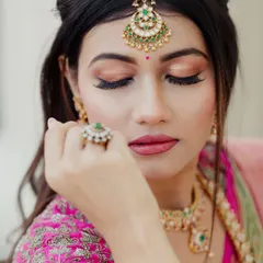 A close-up beauty shot highlighting the soft pink and gold eye makeup and a perfectly defined maang tikka. This demonstrates my skill in detailed, precise application.