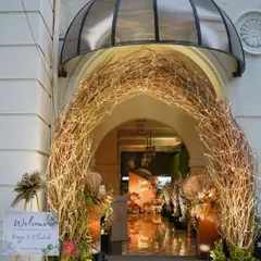 An enchanting rustic-chic entrance for a cocktail party. A twig archway wrapped in fairy lights leads guests into a warmly lit space, setting a magical tone for the evening.