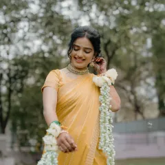 A beautiful portrait of the bride in her yellow Haldi saree, adorned with delicate floral jewelry. Her shy smile captures the essence of a bride-to-be.