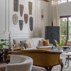 We layered the living room with antiques and collectibles from our client's personal collection, including a striking gallery of masks. This approach ensures the home truly tells the story of the people who live there.