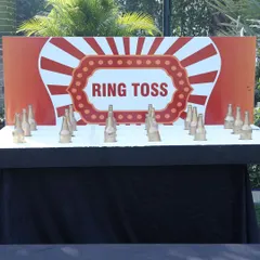 The classic ring toss game, set up with glass bottles and a professionally designed backdrop. It's a game of skill that always draws a crowd at carnival-themed events.