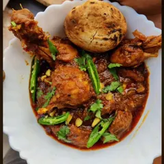 A comforting bowl of my Desi-style homemade chicken curry, prepared with a rich blend of spices and garnished with fresh green chilies. This is a popular main course option for house parties and family gatherings.