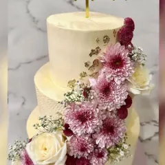 This 10kg, three-tier engagement cake is a vision of romance. It features a cascade of fresh chrysanthemums and roses, accented with baby's breath and delicate gold leaf for an elegant finish.