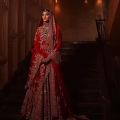 This full-length shot captures the grandeur of a traditional red bridal lehenga. The makeup is designed to be striking from a distance yet flawless up close, ensuring the bride is the center of attention.
