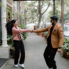A playful moment captured as a couple holds hands and dances on a city sidewalk. Their genuine smiles and movement show the fun, relaxed vibe of my couple sessions.