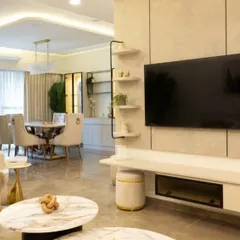 A luxurious living room from the Bren Zahara project, where a beige and marble TV unit is complemented by soft, curved wall sconces. The design creates a sophisticated and serene ambiance for relaxation.