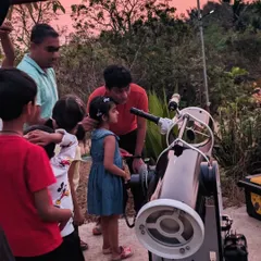 An instructor guides a young girl and her family, helping them find planets and stars. Our small group sizes ensure everyone gets a personal and engaging astronomy experience.