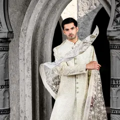 An ethereal ivory sherwani with delicate embroidery, paired with a matching embroidered dupatta. This look is perfect for a groom who wants a sophisticated and regal look for his wedding day.