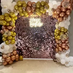 A close-up of the rose gold and gold balloon arrangement against the shimmering backdrop.