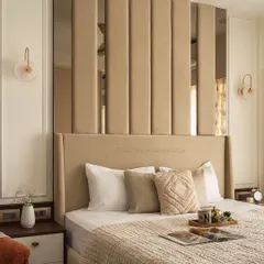 This master bedroom exudes warmth and sophistication. The focal point is the tall, beige upholstered headboard with vertical panels, which are interspersed with mirrors to create an illusion of depth and luxury.
