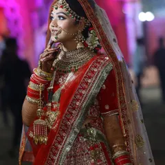 A side profile of our beautiful bride, showcasing the detailed hair and makeup. The dupatta is set perfectly to frame her face, highlighting the flawless finish of her bridal glam.
