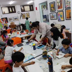 A wide shot of our bustling kids' class, where an instructor provides one-on-one guidance to students working on their individual projects.
