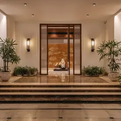 The entrance foyer of Mehalin Farm sets a tone of calm sophistication. A central sculpture is framed by a wooden portal, with marble steps and carefully placed plants guiding the transition from outside to inside.