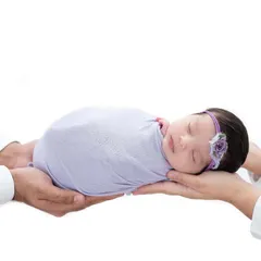 A creative shot where the parents' hands hold their swaddled newborn, creating a sense of safety and love against a clean white background.