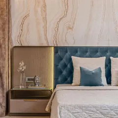 Detail is paramount in our designs. In this master bedroom, a headboard of rich teal velvet is set against a backdrop of Vanilla Onyx marble, with integrated brass accents providing a touch of warmth and opulence.