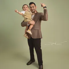 Like father, like son. This dynamic portrait shows a father and his son pointing to the sky, full of energy and joy during their family studio session.