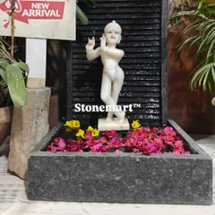 The Kanha Ji fountain decorated with floating flower petals. The contrast between the white marble, dark granite, and colorful flowers is stunning.