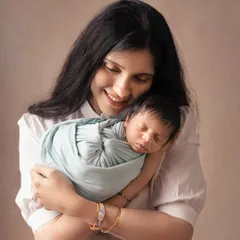 A mother's gentle embrace. This close-up shot captures the pure love and connection as a new mom cuddles her sleeping baby, wrapped snugly in a soft blue swaddle.