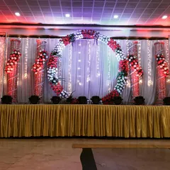 Make a statement with a unique circular floral wreath as your stage centerpiece. This design, using red and white flowers, creates a bold and beautiful focal point for any event.