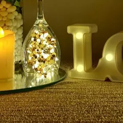 We love using light to create magic. Here, a wine glass filled with gold confetti and fairy lights sits next to an LED candle and marquee letters, creating a sparkling and glamorous table centerpiece.
