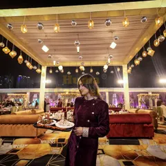 A member of my service staff carries a tray of appetizers through a grand, beautifully lit event space. My team is trained to navigate large crowds efficiently while providing attentive service.