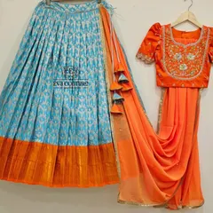 A vibrant half-saree set with a blue Ikat-style lehenga and a contrasting orange blouse and dupatta.