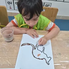 I create, I learn! Here, a child is using a cotton swab to practice Aboriginal dot painting. This activity is part of our exploration of world cultures and art forms, and it's also great for developing fine motor control.