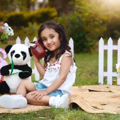 This sweet three-year-old is listening to tunes on a vintage radio during her sunny outdoor picnic shoot.