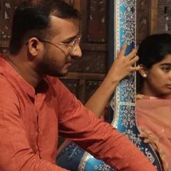A student accompanies a guest artist on the tanpura during a baithak. This provides invaluable experience in learning how to support a lead performer and be part of a live ensemble.