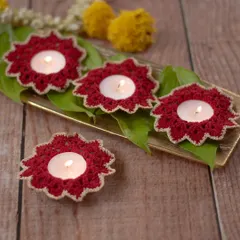 A set of four maroon crochet diya holders arranged on a tray. The intricate design and rich color make them a beautiful centerpiece for your festive table settings.
