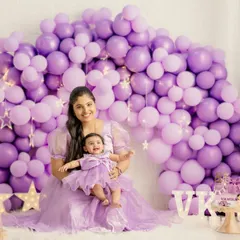 A beautiful mother-daughter portrait from a first birthday session. They are dressed in matching purple outfits against a stunning balloon arch, creating a cherished memory.