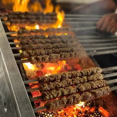 Rows of mutton seekh kebabs sizzling over a fiery charcoal grill, showcasing the authentic cooking process.