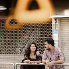A creatively framed shot of a couple leaning against a railing, their conversation captured through a foreground element.