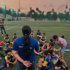 A female sports psychologist leads a session with a group of young players at dusk. This image shows that learning about the mental side of the game is an integral part of our training.