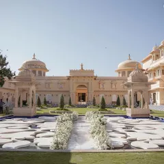 A breathtaking Anand Karaj ceremony at The Oberoi Udaivilas. The aisle, lined with pristine white florals, leads to a serene water body, perfectly framing the majestic palace architecture for this destination wedding in Udaipur.