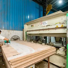 A worker operates our hydraulic press, which is used to laminate surfaces onto plywood. This ensures a bubble-free, durable finish for desktops and cabinet doors that can withstand daily office use.