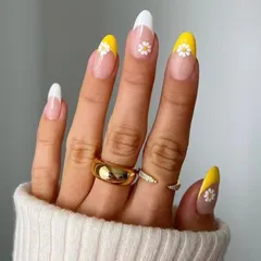 A cheerful and sunny French manicure featuring bright yellow tips on some nails and classic white on others. The look is finished with a delicate hand-painted daisy on the accent nails for a touch of floral fun.