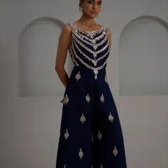 This navy blue jumpsuit is a chic and modern alternative to traditional festive wear. The intricately embroidered bodice provides the drama and elegance of a blouse, while the wide-leg pants offer comfort and a sleek silhouette.