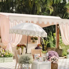 We create cozy, stylish lounge areas for guests to relax. This vignette features a scalloped-edge parasol, comfortable wicker seating with floral cushions, and abundant arrangements of roses and baby's breath.