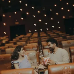 A playful moment sharing popcorn in a theatre. This shot adds a fun, candid element to the cinematic pre-wedding shoot, showing the couple's relaxed chemistry.